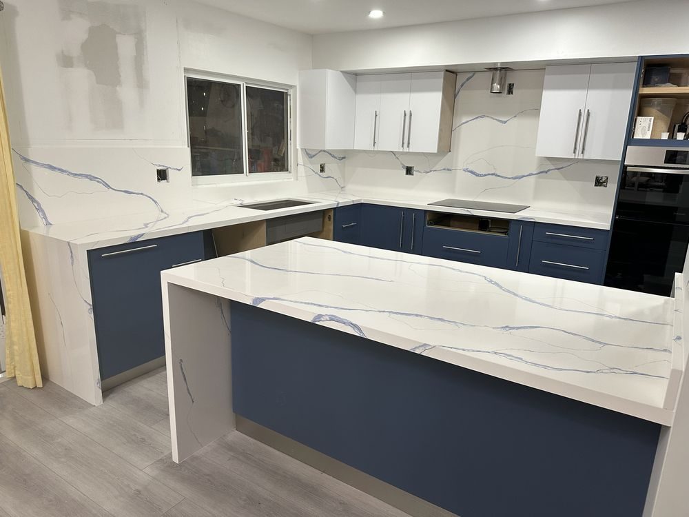 Navy kitchen with a blue-veined white quartz waterfall island and full backsplash